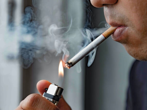 A close-up image of a person lighting a cigarette with an emergency restoration lighter, with smoke visibly emanating from the cigarette.